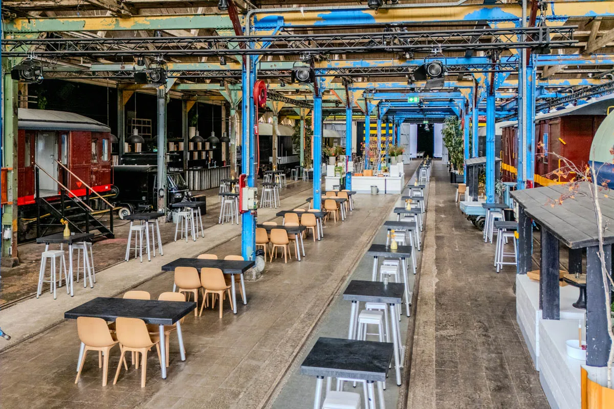 Industri&euml;le evenementenhal De Rijtuigenloods met originele treinrails, hoge tafels en zitplekken voor een zakelijk evenement